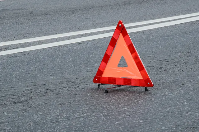Triunghi reflectorizant roșu de avertizare, așezat pe asfalt