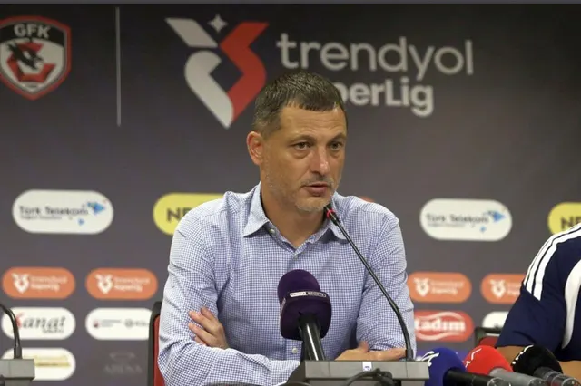 Bărbat în cămașă albastru-deschis la o conferință de presă, în fața panoului Trendyol Süper Lig