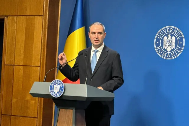 Alexandru Nazare vorbind la pupitrul Guvernului României, lângă drapelul tricolor