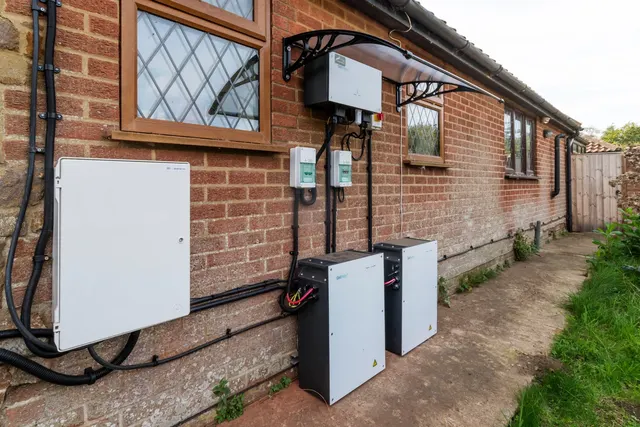 Baterii de stocare a energiei și un invertor montate pe peretele de cărămidă al unei case