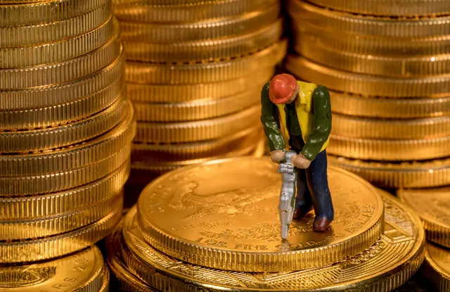 Teancuri de monede de aur și o figurină de muncitor cu un picamăr pe una dintre ele