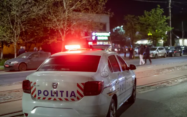 Mașină de poliție cu girofarurile aprinse, oprită pe o stradă noaptea