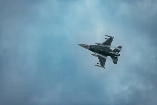 Avion de vânătoare în zbor, pe un cer albastru cu nori