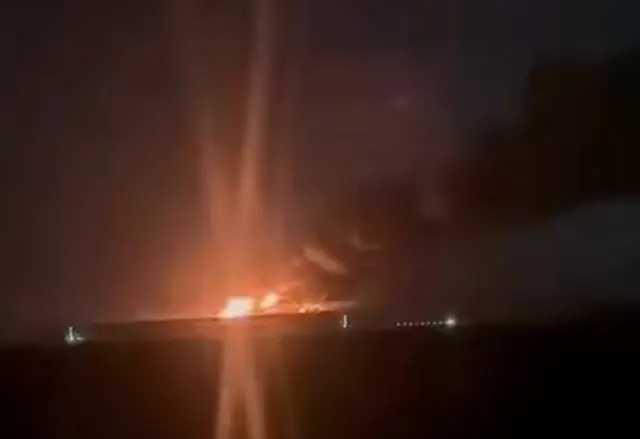 Captură video: incendiu puternic la orizont, noaptea, cu flăcări portocalii