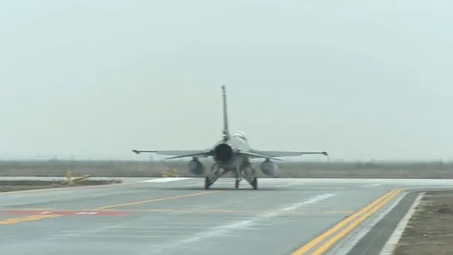 Avion de vânătoare F-16 pe pista unei baze aeriene, sub un cer înnorat