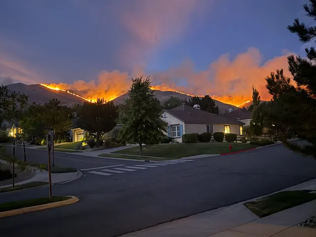 Incendiu de vegetație pe dealurile din spatele unui cartier de case, la apus, în Nevada