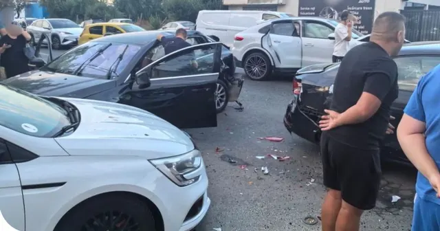 Mașini avariate pe o stradă după un accident, cu oameni care privesc pagubele