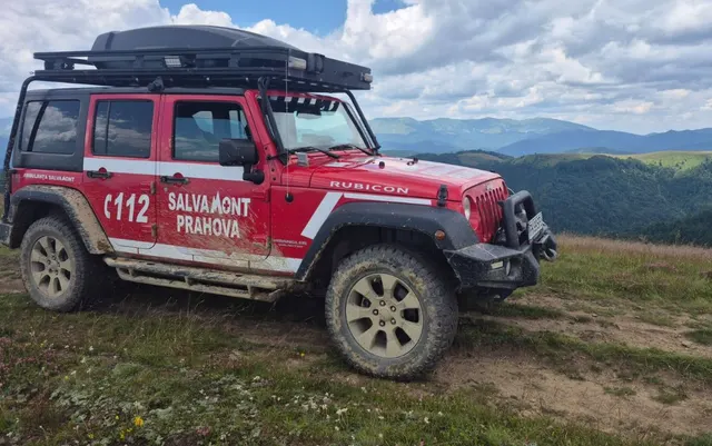 Autospecială Salvamont Prahova, un Jeep roșu cu inscripția 112, pe o pajiște montană