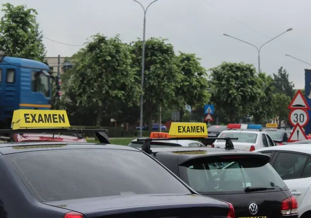 Mașini de școală de șoferi cu panouri „Examen” pe plafon, într-o parcare