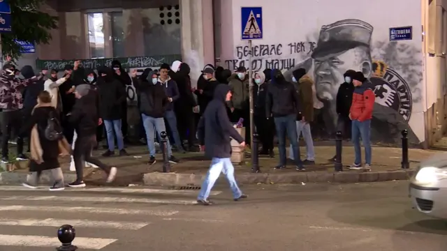Oameni adunați seara în fața unui mural cu Ratko Mladić, într-un oraș din Serbia