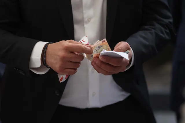 Mâinile unui bărbat în costum numărând bancnote