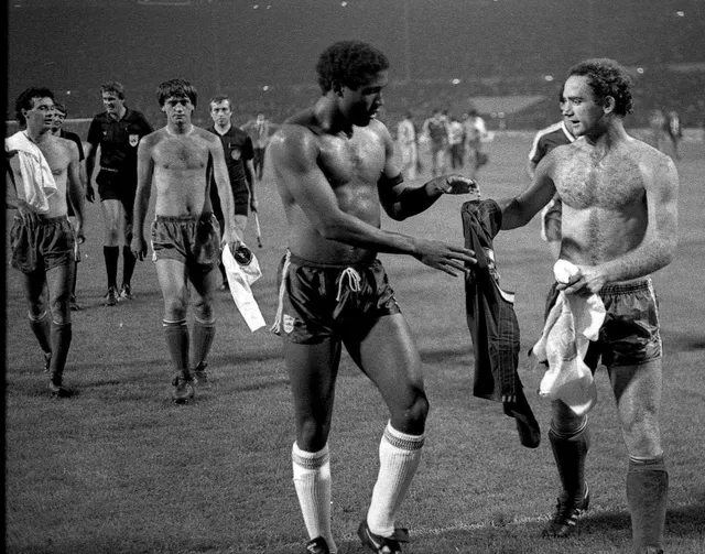 Fotbaliști la bustul gol schimbând tricourile după un meci, într-o fotografie veche alb-negru