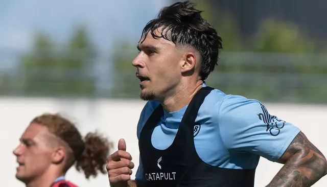 Fotbalist cu părul ondulat, în tricou albastru și vestă de monitorizare, la antrenament
