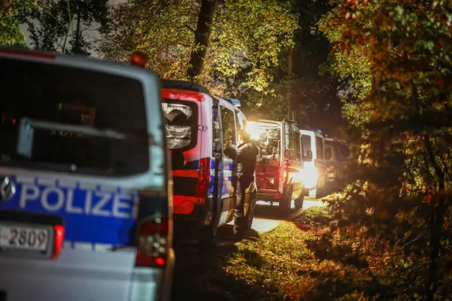 Autospeciale de poliție cu inscripția „Polizei”, parcate noaptea la marginea unei păduri