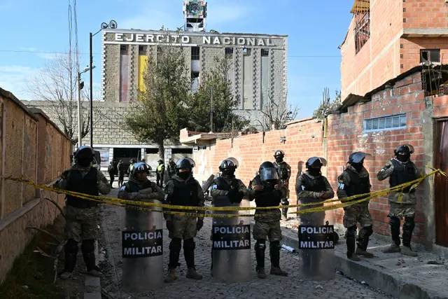 Polițiști militari cu scuturi inscripționate „Policía Militar”, în fața unei clădiri pe care scrie „Ejército Nacional”