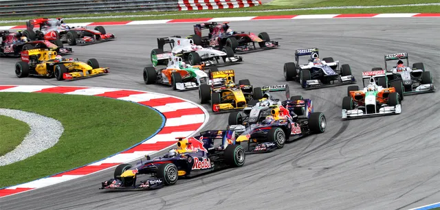 Monoposturi de Formula 1 în pluton, într-un viraj cu borduri roșu-albe