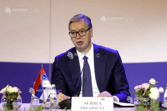Bărbat cu ochelari, la o masă de conferință cu plăcuța „Serbia President” și drapelul Serbiei