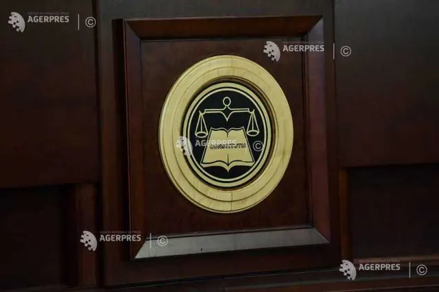 Emblema aurită a Curții Constituționale, pe un panou de lemn închis la culoare