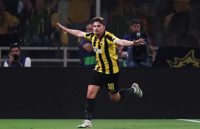 Fotbalist în tricou cu dungi galben-negre, cu numărul 18, celebrând cu brațele deschise