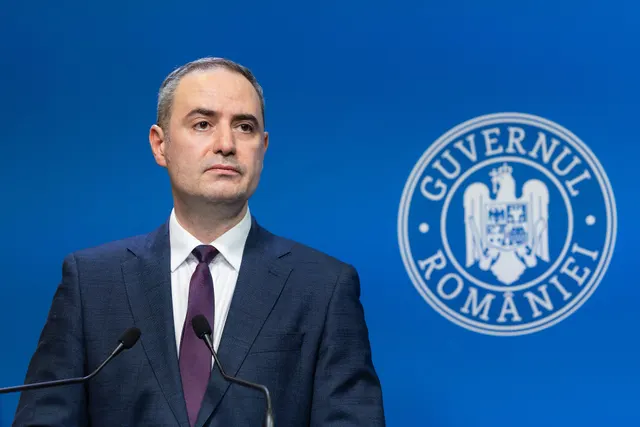 Alexandru Nazare la un briefing de presă, în fața siglei Guvernului României