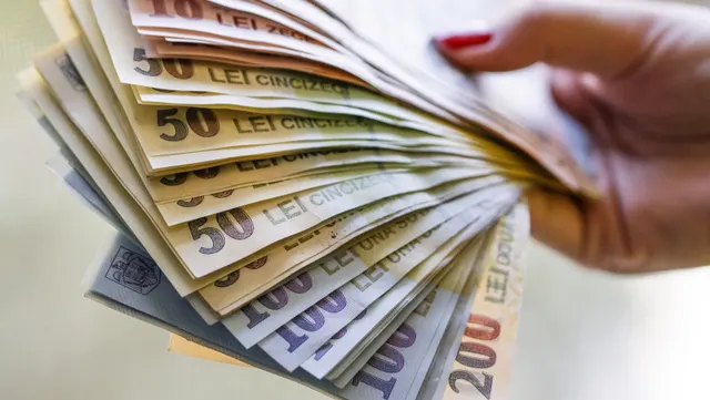 Mână care ține un evantai de bancnote românești de 50, 100 și 200 de lei