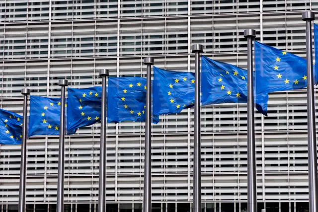 Drapelele UE fluturând în fața clădirii Berlaymont a Comisiei Europene, cu fațada din lamele metalice