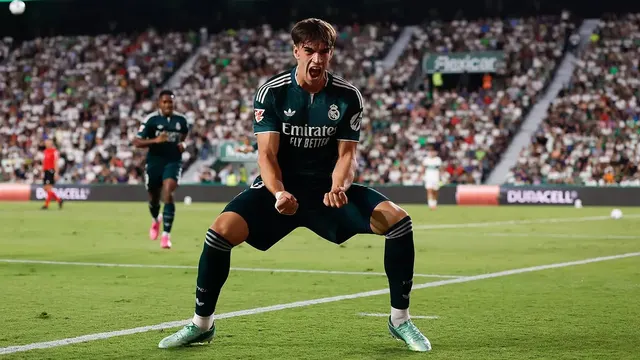 Fotbalist în echipament verde închis, cu sponsorul „Emirates Fly Better”, ghemuit și strigând pe teren