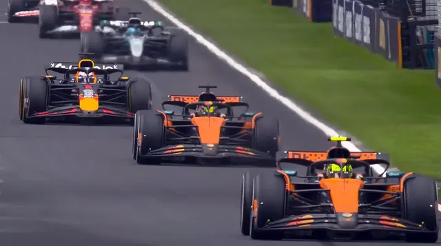 Monoposturi de Formula 1 în pluton pe circuit, cu două mașini portocalii în prim-plan
