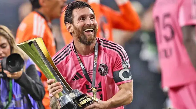 Messi, în tricoul roz al lui Inter Miami, cu banderola de căpitan, zâmbind cu un trofeu în mână