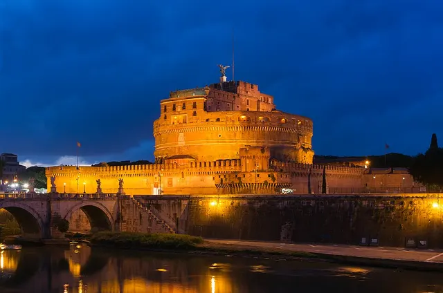 Castelul Sant'Angelo din Roma, luminat la amurg, cu podul de piatră peste Tibru în prim-plan