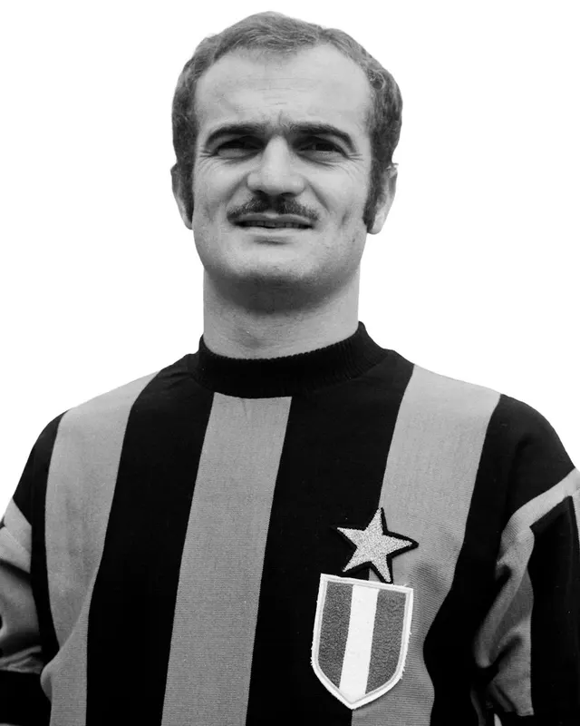 Portret alb-negru al unui fotbalist cu mustață, în tricou cu dungi verticale și o stea pe piept