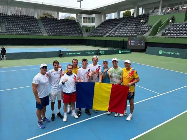 Echipa României de Cupa Davis pozând pe un teren de tenis albastru, cu tricolorul desfășurat