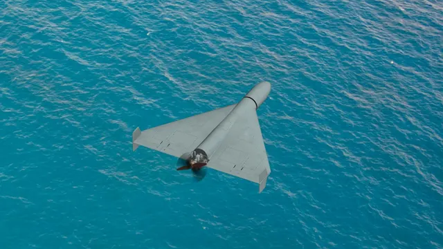 Dronă cu aripi în formă de deltă, văzută de sus, în zbor deasupra apei mării