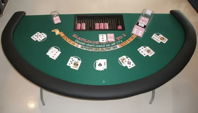 Masă de blackjack cu postav verde și cărți de joc împărțite, văzută de sus