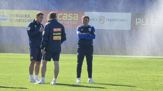Trei membri ai staffului în geci bleumarin discutând pe un teren de antrenament, lângă bannere Banca Transilvania