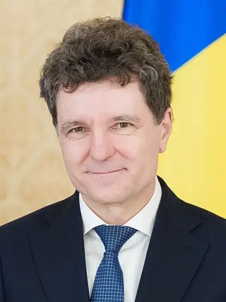 Nicușor Dan, în costum și cravată albastră, în fața drapelului României, în 2026