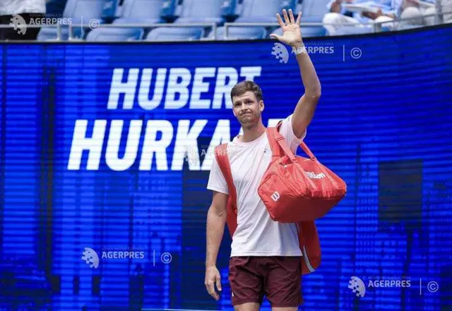 Hubert Hurkacz, în tricou alb, cu o geantă roșie pe umăr, salutând la intrarea pe teren, sub numele lui pe ecran