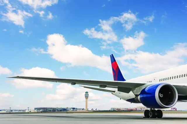 Avion de linie cu însemnele Delta pe coadă, pe pista unui aeroport, sub cer cu nori