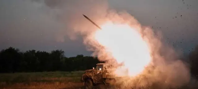 Rachetă lansată dintr-un vehicul militar pe un câmp, cu o flacără puternică și nori de fum
