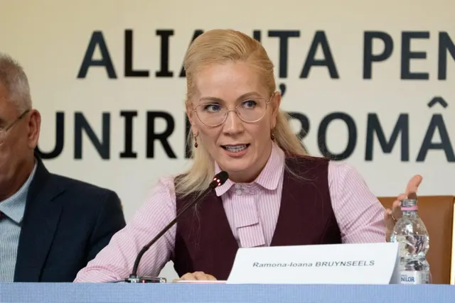 Ramona-Ioana Bruynseels vorbind la microfon, în fața panoului Alianța pentru Unirea Românilor