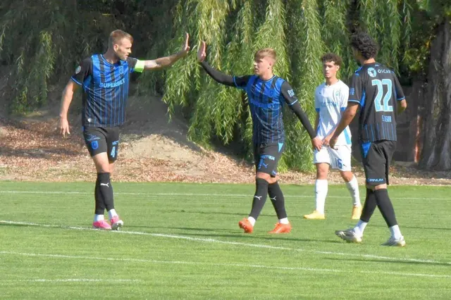Fotbaliști în echipament negru cu albastru bătând palma pe un teren de antrenament, lângă un jucător în alb