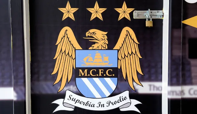Emblema Manchester City, cu vulturul, cele trei stele și deviza „Superbia in Proelio”