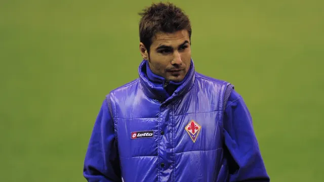 Bărbat în vestă mov cu emblema Fiorentinei, pe un teren de fotbal