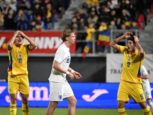 Doi fotbaliști în echipament galben, cu mâinile la cap, lângă un adversar în alb, pe un stadion cu tricolori
