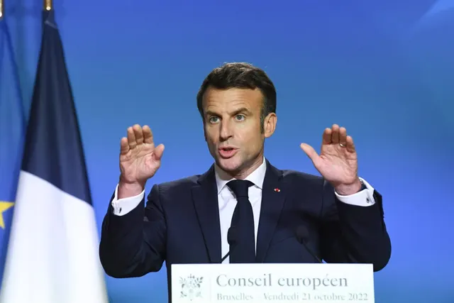 Bărbat în costum gesticulând la un pupitru cu inscripția „Conseil européen”, lângă drapelul Franței