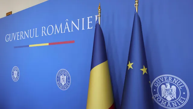 Panoul albastru cu inscripția „Guvernul României”, cu drapelele României și UE în față