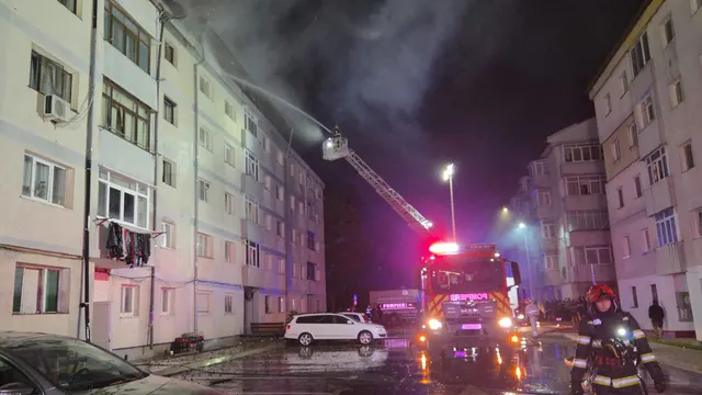 Incendiu noaptea la ultimul etaj al unui bloc, cu o autoscară a pompierilor și fum dens