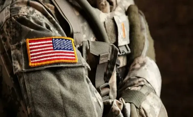 Uniformă militară de camuflaj, cu ecusonul drapelului SUA pe mânecă, în prim-plan