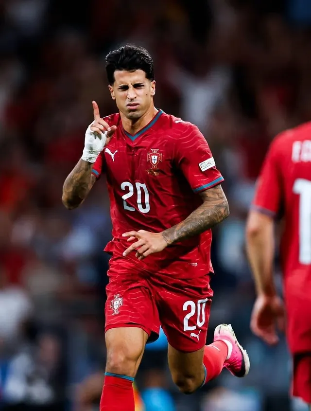 Fotbalist în echipament roșu, cu numărul 20, ducând degetul la buze în timpul unui meci