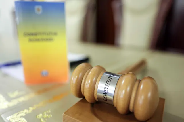 Un exemplar al Constituției României și un ciocănel de judecător, pe o masă